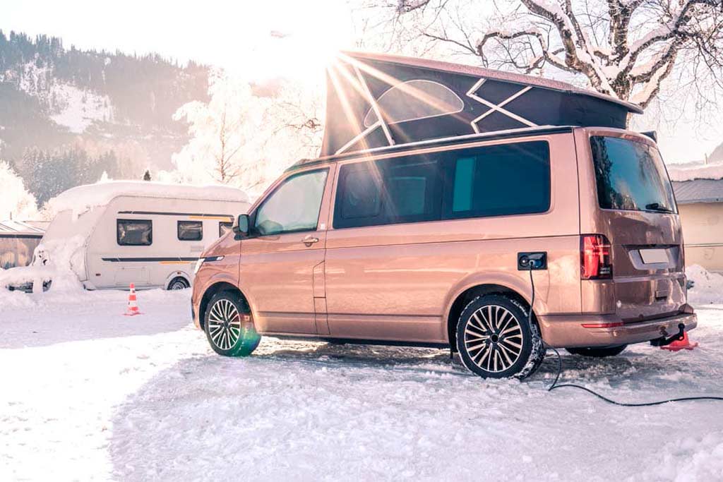 Furgoneta circulando por carretera cubierta de nieve.