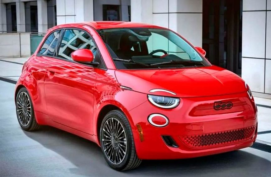 Coche eléctrico urbano compacto (“e-car”) circulando por una calle moderna en una ciudad europea.